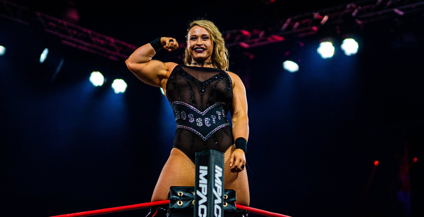 Wrestler flexing on the ring ropes in front of stage lighting